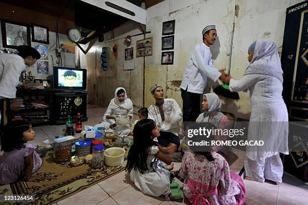 Rasyid , an Indonesian fisherman, welcomes a relative while his wife Sukaisih serves guests at their residence in Jakarta to celebrate Eid-al-Fitr on...