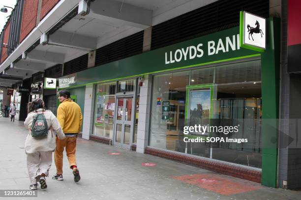 Couple walking past a branch of Lloyds Bank in London.