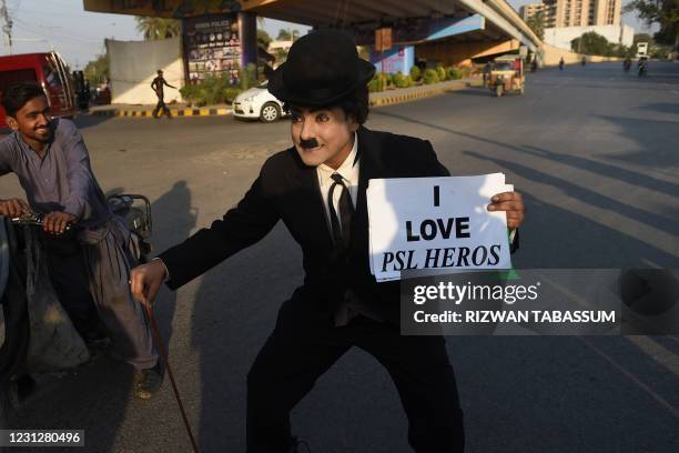 Cricket fan Sherry Khan, dressed up as silent film star Charlie Chaplin, arrives to watch the first T20 Pakistan Super League match between Karachi...