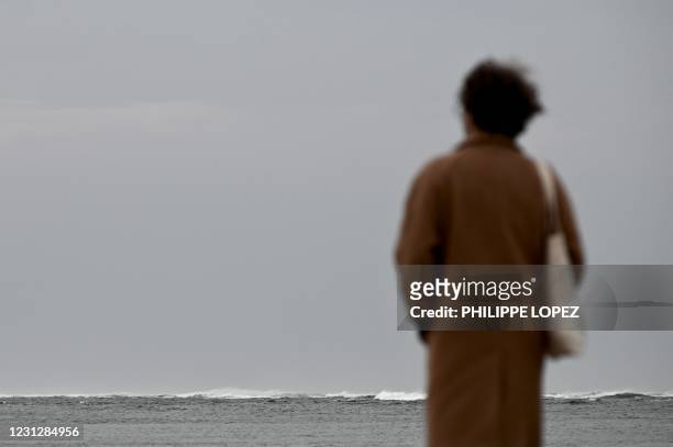 Woman looks at the Atlantic Ocean from the beach in La Teste-de-Buch, southwestern France, on February 20, 2021.