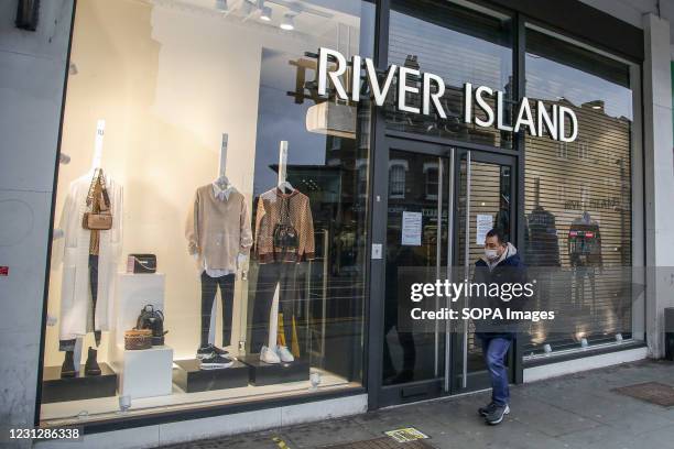 Man wearing a face mask as a precaution against the spread of covid-19 walks past a branch of River Island in London. Non-essential retail businesses...