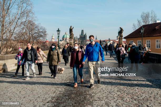 People walk over the Charles bridge in Prague on a sunny February 20 amid the coronavirus Covid-19 pandemic.