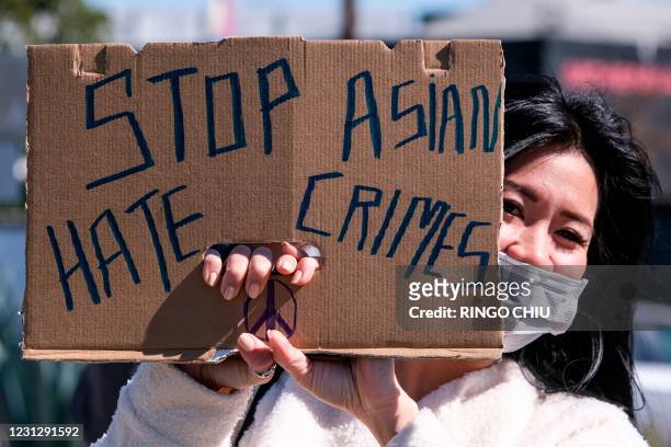 Demonstrator wearing a face mask and holding a sign takes part in a rally to raise awareness of anti-Asian violence, near Chinatown in Los Angeles,...