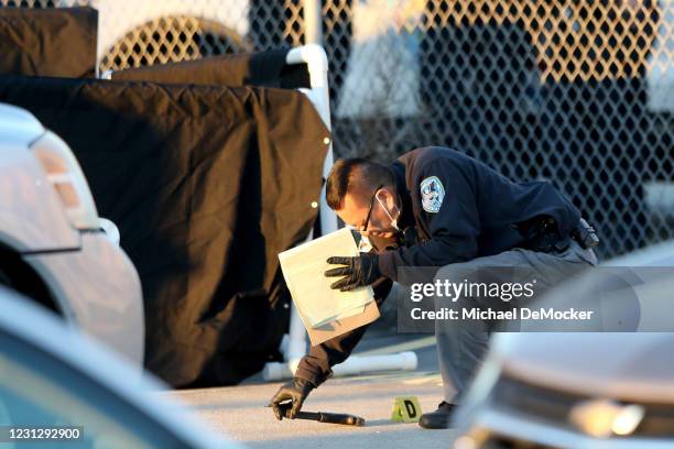 Crime scene technician with the Jefferson Parish Sheriffs Office examines a handgun on the ground next to the screened body of a victim in the...
