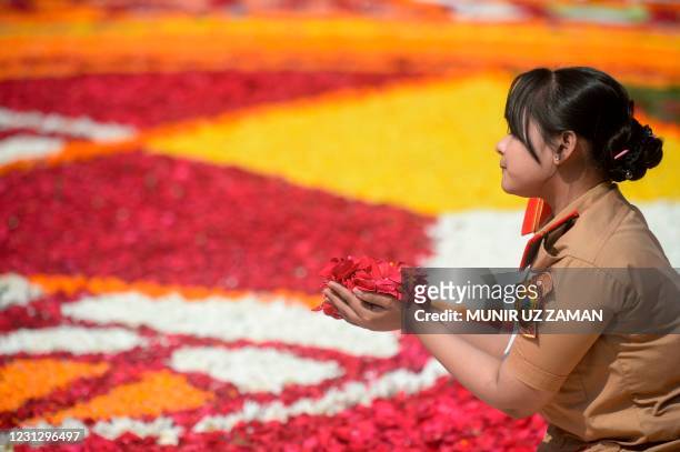 Woman holds flower petals for a display at Bangladesh Central Language Martyrs' Memorial monument in homage to the martyrs of the 1952 Bengali...