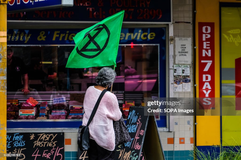A protester walks past a butcher shop while holding...