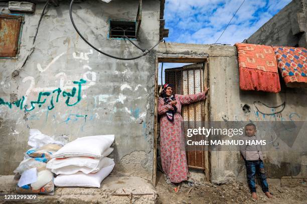 Woman stands through the doorway to her home next to sacks of flour received received as humanitarian aid provided by the United Nations Relief and...