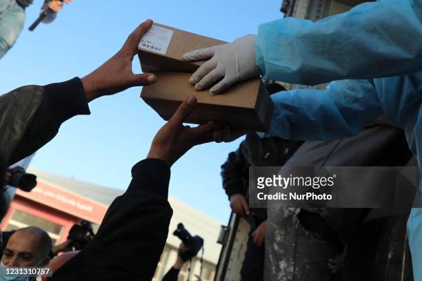 Workers unload from a truck, boxes of Russian-made Sputnik V vaccine doses from the UAE, upon its arrivel in the Gaza Strip via the Rafah crossing...