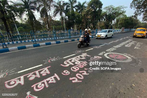 People ride past the road graffiti made at Rabindra sadan area on the occasion of International Mother Language Day. Road graffitis are made on the...