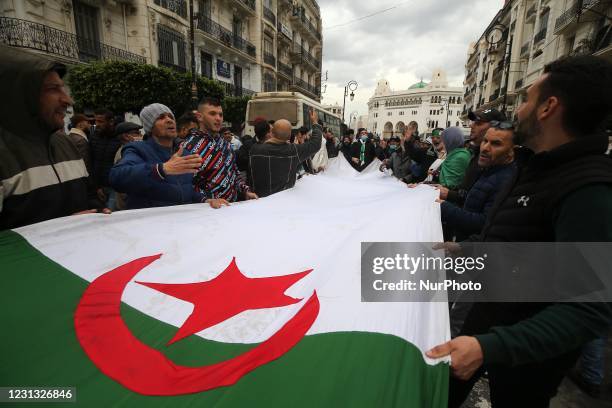 Algerians hold a national flag with the Arabic inscription bearing the mention as they march to mark the second anniversary of popular protests in...