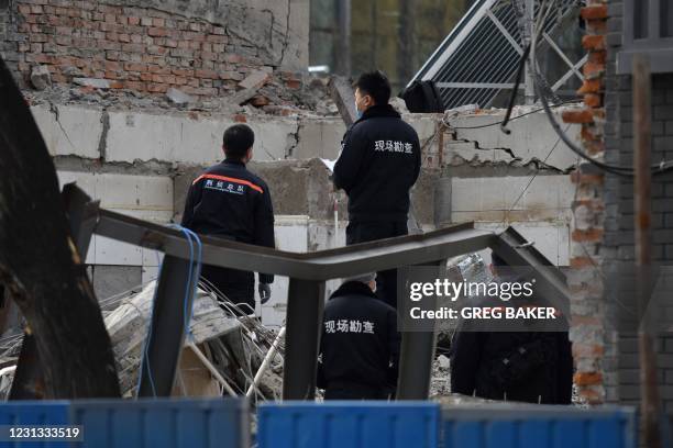 Investigators stand on the rubble of a restaurant which was destroyed in an explosion, near the Zhongnanhai leadership compound in Beijing on...