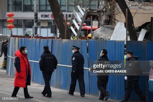 Investigators walk outside the remains of a restaurant which was fenced off after it was destroyed in an explosion, near the Zhongnanhai leadership...