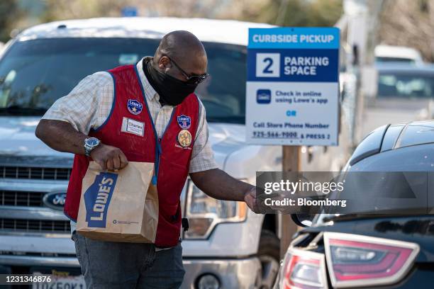 Worker wearing a protective mask delivers a purchase to a customer at the curbside pickup area of a Lowe's store in Concord, California, U.S., on...