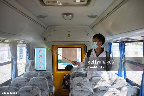 This photo taken on February 23, 2021 shows a worker spraying disinfectant inside a school bus in Yongchuan, in central China's Hunan province, as...