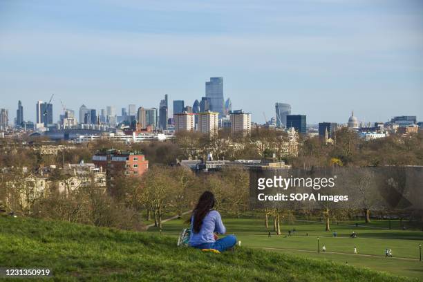 Woman enjoys the view from Primrose Hill in London on a sunny day.