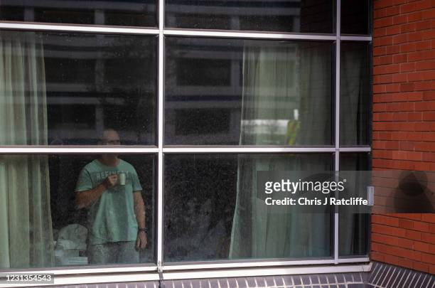 Hotel guest looks out of their room window as they continue their quarantine period at the Novotel hotel on February 24, 2021 in London, England....