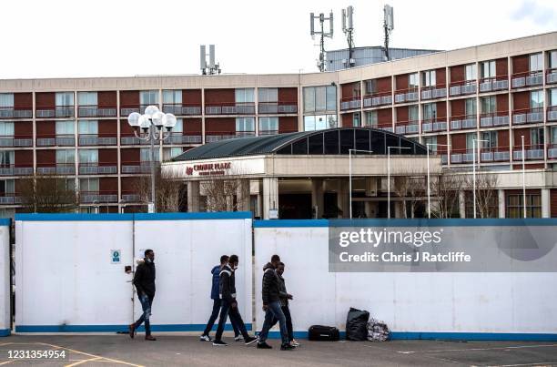Asylum seekers exit the Crowne Plaza hotel through an exterior perimeter wall that has been installed whilst they stay at the hotel on February 24,...
