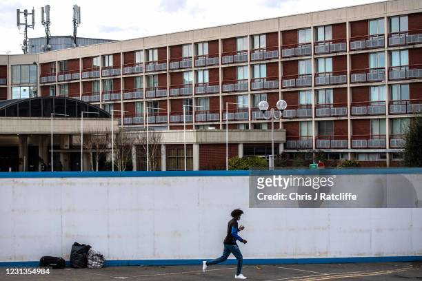 Asylum seekers exit the Crowne Plaza hotel through an exterior perimeter wall that has been installed whilst they stay at the hotel on February 24,...