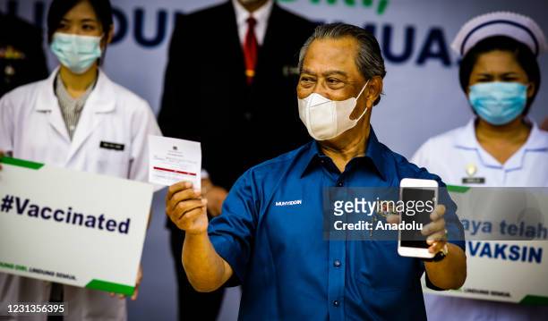 Prime Minister of Malaysia, Tan Sri Muhyiddin Yassin show his immunization passport after undergoing the Covid-19 vaccine process in Putrajaya,...