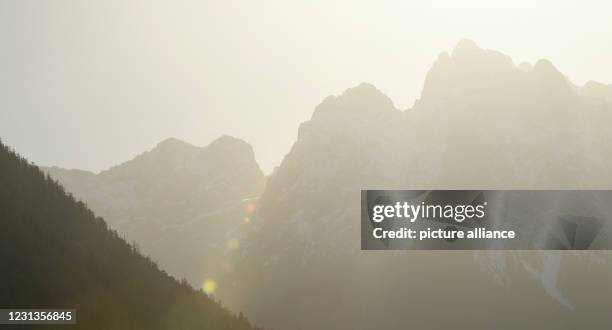 February 2021, Bavaria, Mittenwald: The sky above the mountains in the Karwendel is clouded by the Sahara sand in the air. Dust from the African...