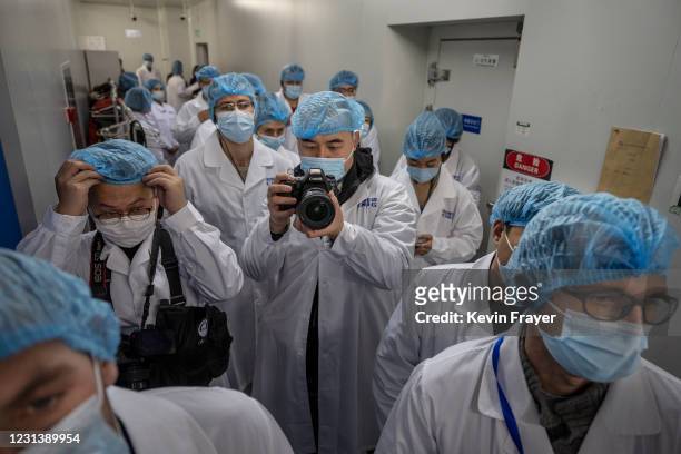 Journalists wear protective clothing as they wait to enter the packaging area at Sinopharm CNBG's inactivated SARS-Cov-2 vaccine COVID-19 production...