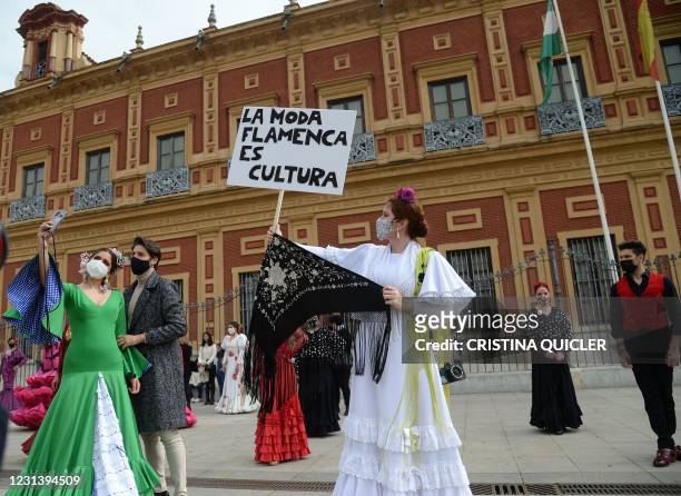Woman in a flamenco dress holds up a placard reading "Flamenco fashion is culture" during a protest to shed light on the difficulties the flamenco...