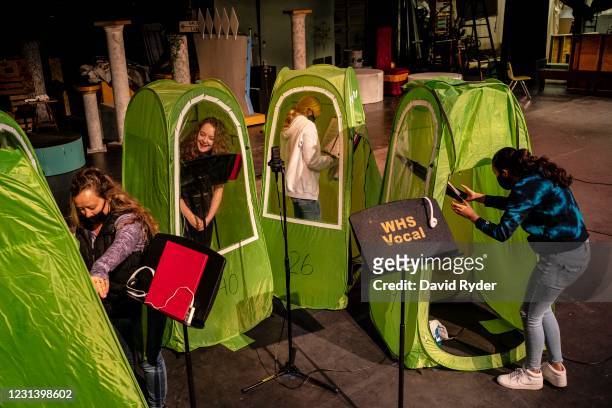 Choir director Dawn McCorkmick and students Emma Banker, Jessi McIrvin, and Valerie Sanchez prepare pop-up tents during choir class at Wenatchee High...
