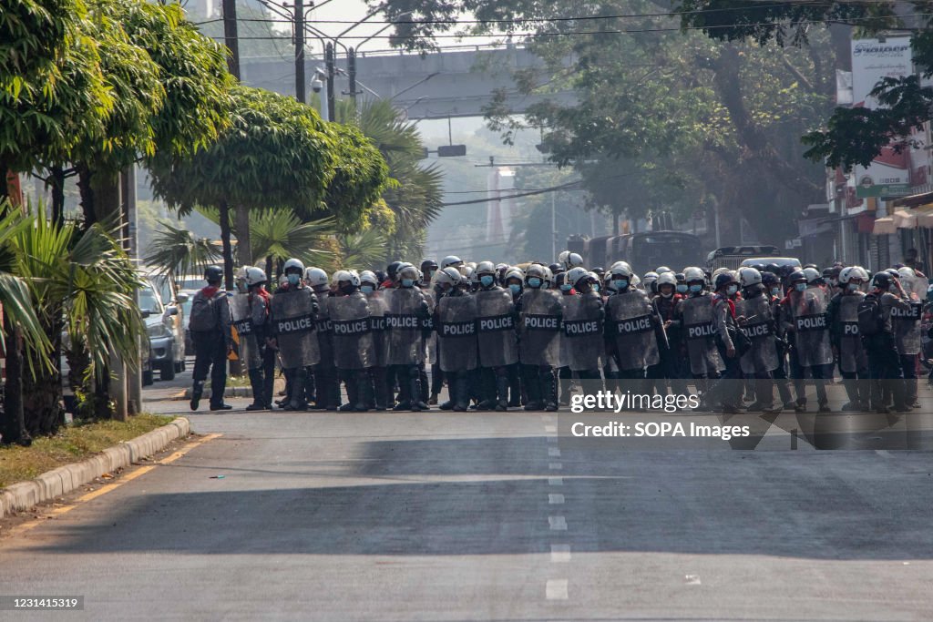 Riot police officers stand ready to arrest protesters and...