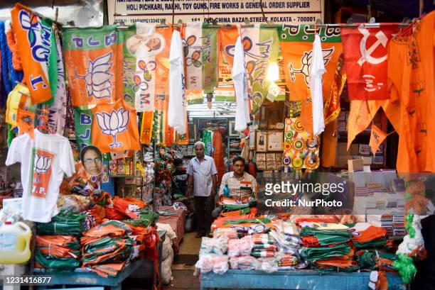Shopkeeper displays campaigning material of political parties for sale ahead of the West Bengal state legislative assembly elections, Kolkata, India,...