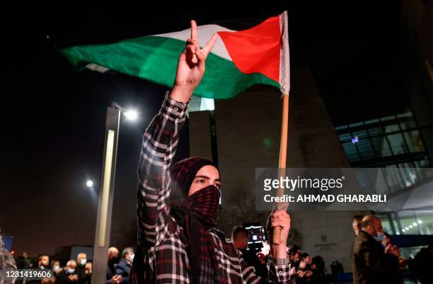 Demonstrator raises a hand with the victory gesture while holding a Palestinian flag outside the Haifa District Court in Israel's northern...