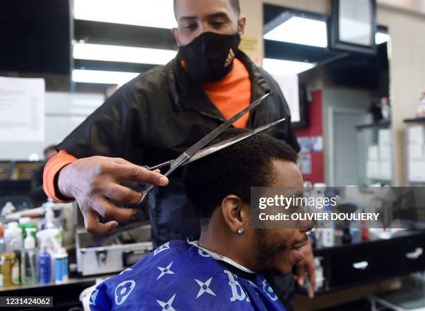 Mike Brown cuts the hair of Kendrick Furbush at The Shop Hair Spa in Hyattsville, Maryland on February 25, 2021. - Brown carefully guides his trimmer...