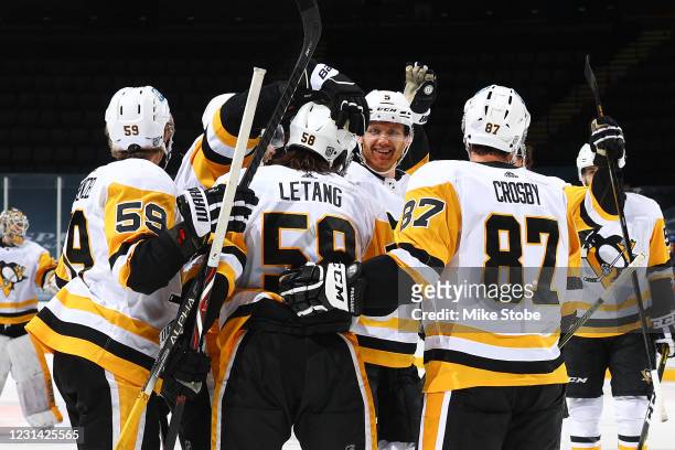 Kris Letang of the Pittsburgh Penguins is congratulated by his teammates after scoring the game-winning goal in overtime to defeat the New York...