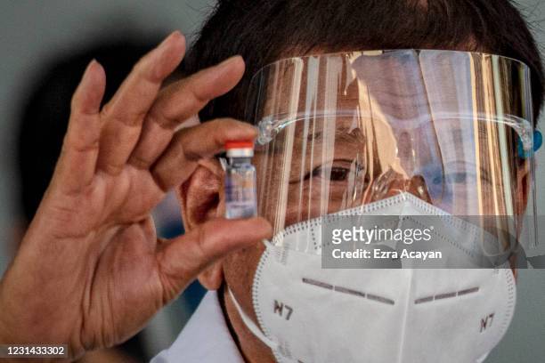 Philippine President Rodrigo Duterte holds up a vial of Sinovac Biotech's COVID-19 vaccines as he witnesses the arrival of a shipment of the vaccines...