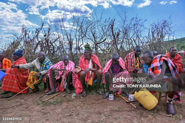 Elders from the Kenyan Maasai tribe sit in a group to partake in tradition beer as they attend a rite of passage for younger males, to mark the...