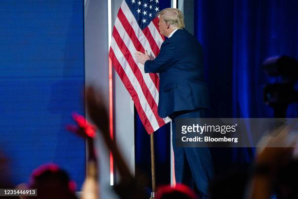 Former U.S. President Donald Trump hugs and kisses an American flag as he walks on stage to speak during the Conservative Political Action Conference...