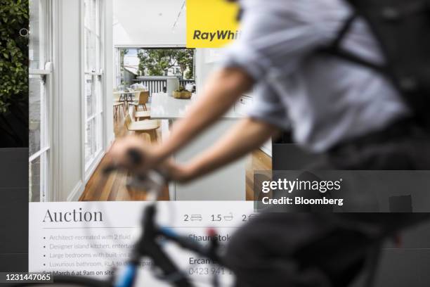 Cyclist rides past an 'auction' real estate sign outside a house in the Newtown suburb of Sydney, Australia, on Tuesday, Feb. 23, 2021. Australia's...