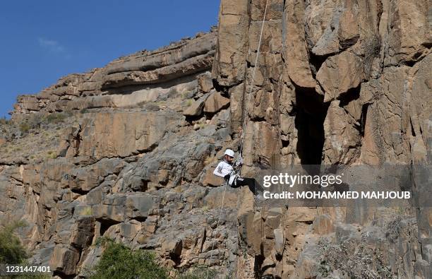 Haitham al-Abri rappels down a mountain in the village of Misfat al-Abriyeen situated on the escarpments of Oman's Grand Canyon, on February 8, 2021....