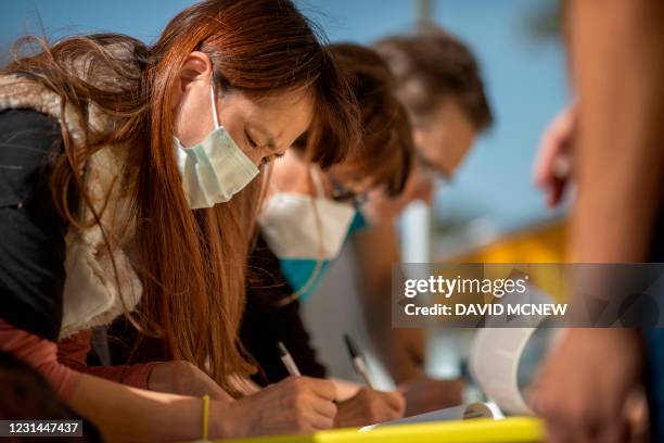 People sign petitions as conservative activists gather signatures in a recall effort against California Governor Gavin Newsom near Pasadena City...