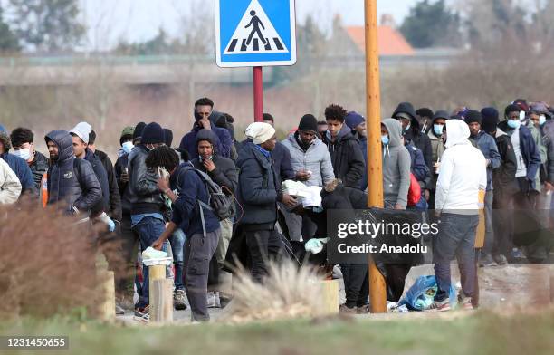 Irregular migrants are seen as they wait in a line to receive food aid in Calais, France on February 25, 2021.