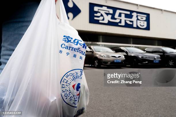 Customer holds a shopping bag on the parking lot outside a Carrefour supermarket. On February 24, Carrefour announced that the sales of...