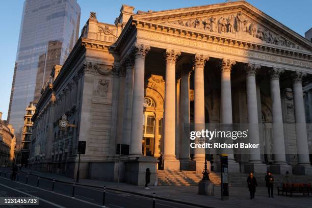 With modern offices of financial institutions behind, an architectural sunlit view of the friezes and Latin inscriptions on the pediment of the Royal...