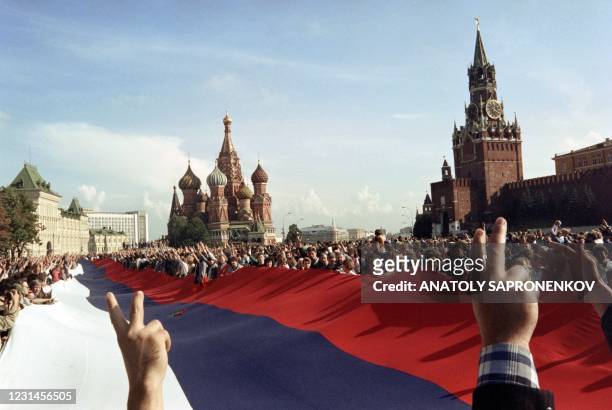 People holding a huge Russian flag flash victory signs on August 22, 1991 on Red Square in Moscow as they celebrate the failure of a hardline...