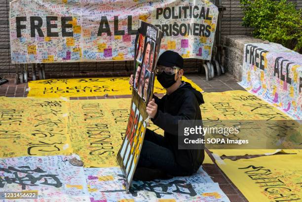 Pro-democracy protester holds a placard in support of the arrested activists outside the West Kowloon Court in Hong Kong. 47 pro-democracy activists...