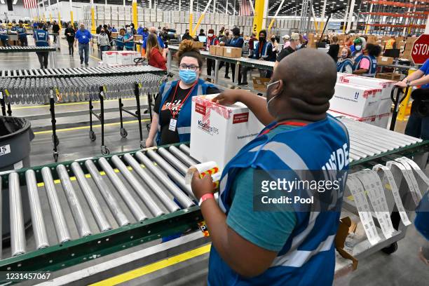The first box containing the Johnson & Johnson COVID vaccine heads down the conveyor to an awaiting transport truck at the McKesson facility on March...
