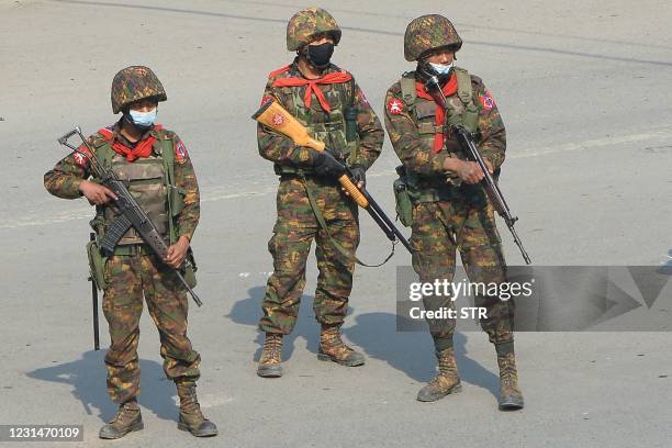 Soldiers carrying firearms look on as protesters hold a demonstration against the military coup in the northwestern town of Kale on March 2, 2021.