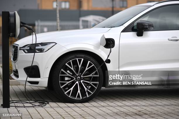 Volvo XC60 hybrid car is seen plugged into a charging point outside a Volvo dealership in Reading, west of London, on March 2, 2021. - Chinese-owned...
