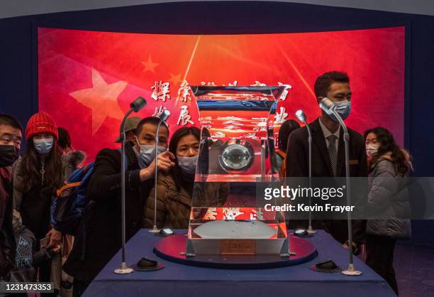 Visitors look and take pictures of a case holding lunar rock and debris recently collected from the Moon by China's space program that is part of a...