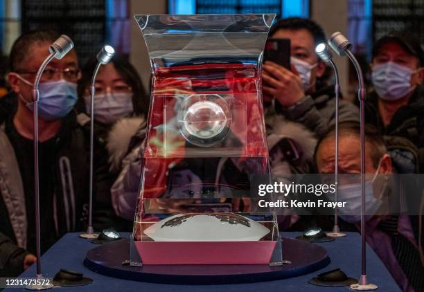 Visitors crowd as they look and take pictures of a case holding lunar rock and debris recently collected from the Moon by China's space program that...