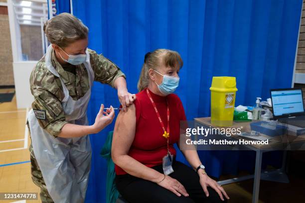 Member of the military administers the AstraZeneca Covid-19 vaccine to a woman at a mass vaccination centre at Holm View Leisure Centre on March 2,...