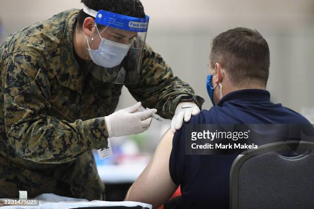Member of the U.S. Armed Forces administers a COVID-19 vaccine to a police officer at a FEMA community vaccination center on March 2, 2021 in...